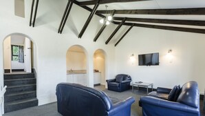 A modern living room with a fireplace, a television, and a staircase leading to a kitchen. - 755 Regal Court (Dunedin)