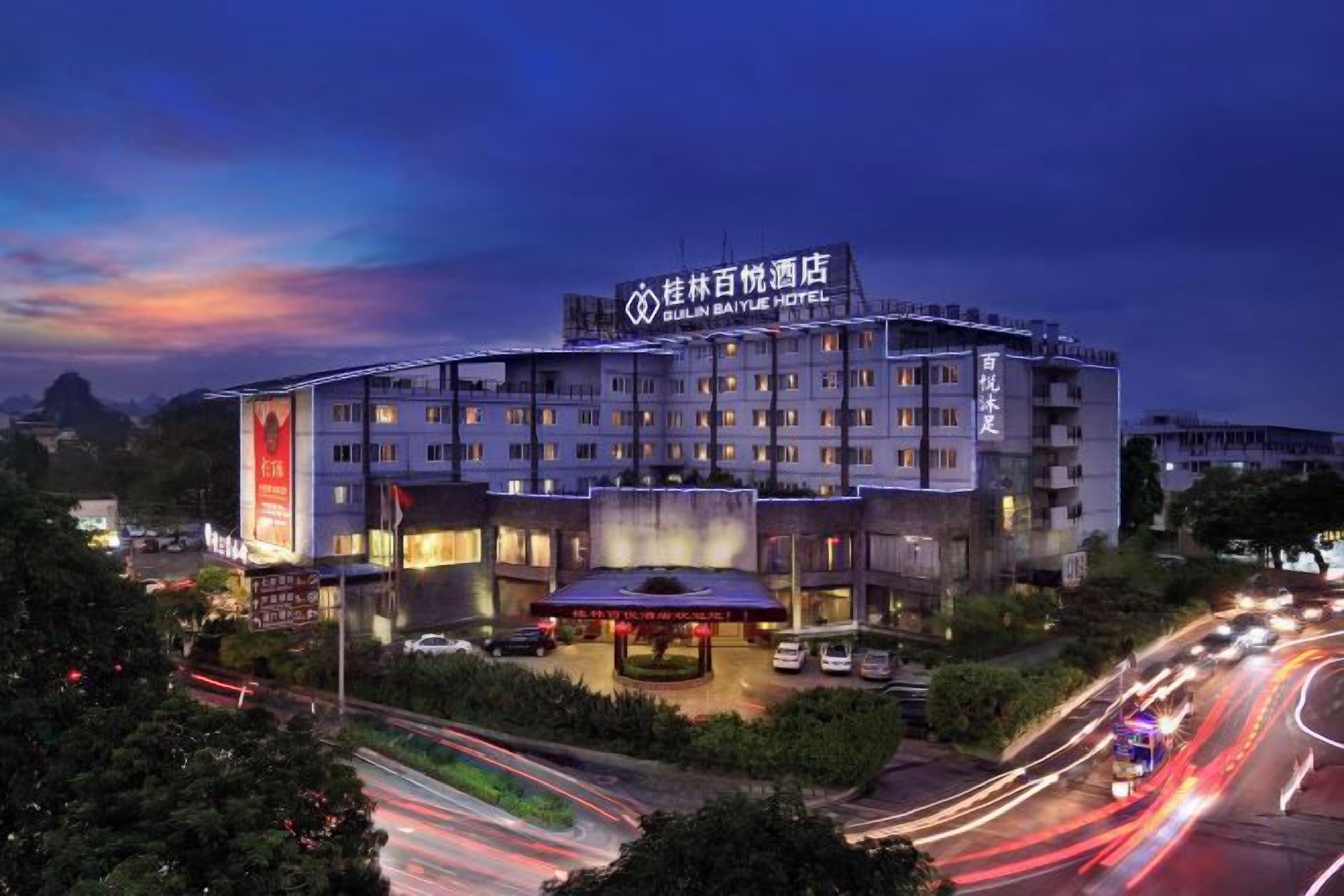 A multi-story hotel with a prominent signage, a covered entrance, and a parking area.