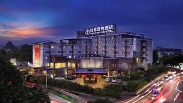 A multi-story hotel with a prominent signage, a covered entrance, and a parking area.