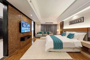 A modern hotel room with a large bed, a sofa, a TV mounted on the wall, and a wooden accent wall.