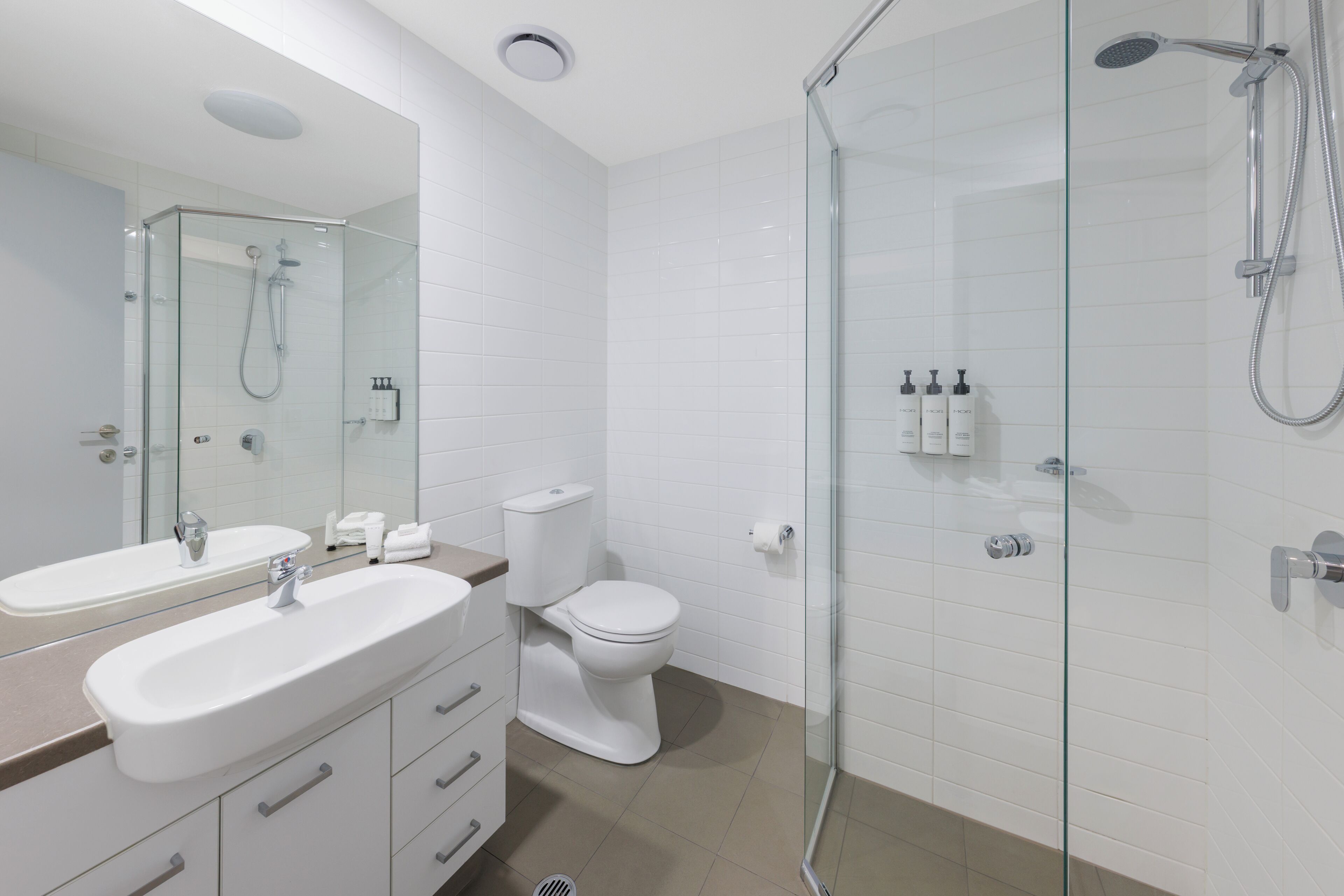 A modern bathroom with a glass-enclosed shower, a white sink, and a toilet.