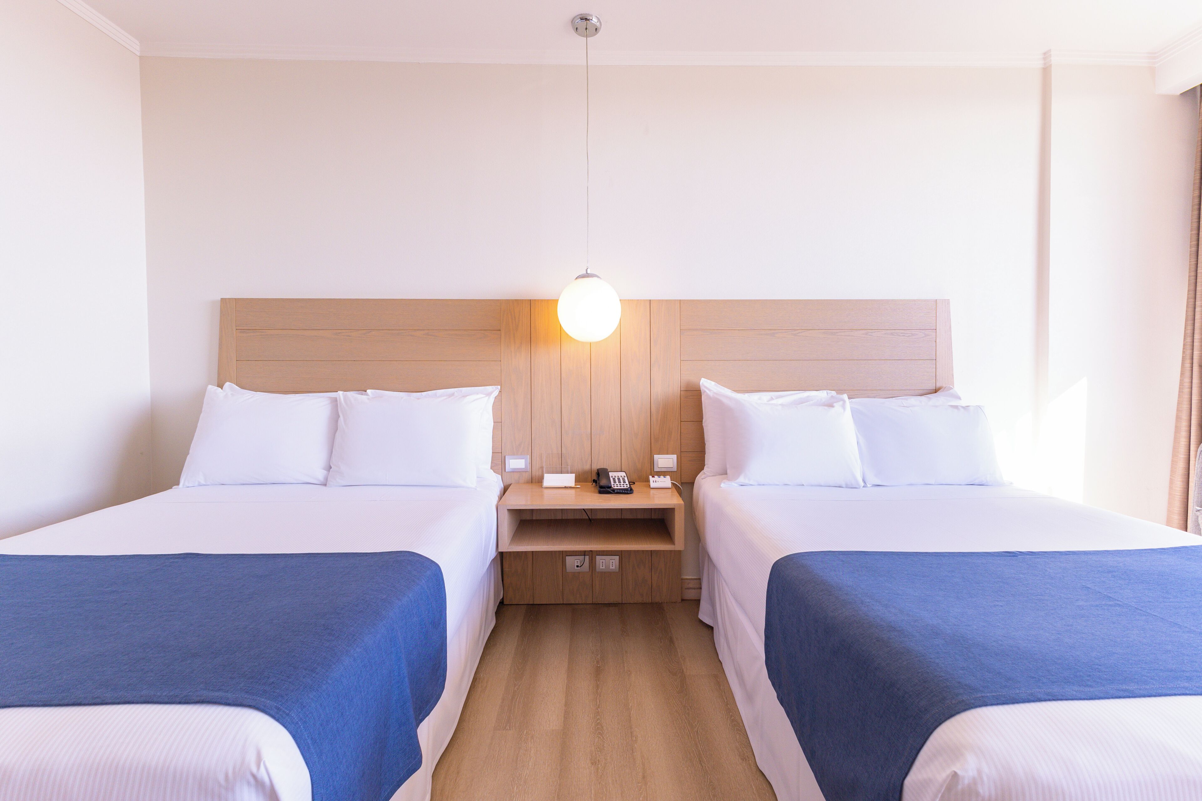 Ein Hotelzimmer mit zwei Betten, einem Nachttisch mit Lampe und einem Holzkopfteil.
