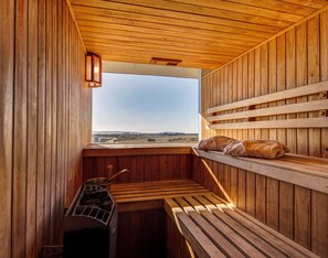 Una sauna de madera con bancos, vistas del paisaje y un calentador de sauna.