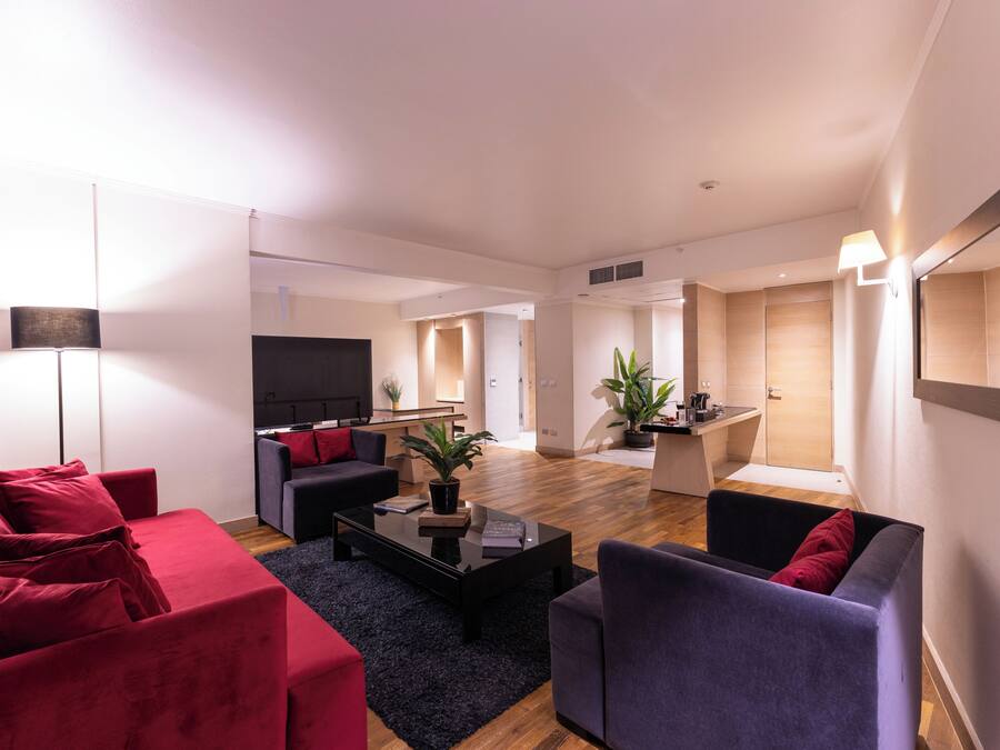 Una sala moderna con sofá, sillones, una mesa de centro y televisión.
