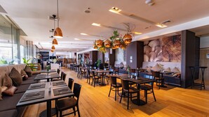 A modern restaurant interior with wooden flooring, multiple dining tables, and a variety of seating options including sofas and chairs. - Wyndham Concepcion Pettra (Hualpén)