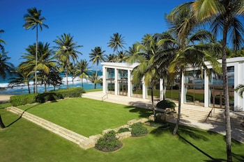 A poolside area with a covered seating area, lounge chairs, and a view of the ocean. at Dorado Beach, a Ritz-Carlton Reserve
