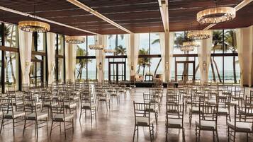 A spacious hall with rows of chairs and large windows overlooking the ocean.
