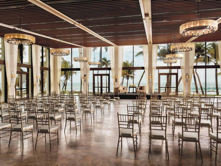 A spacious hall with rows of chairs and large windows overlooking the ocean.