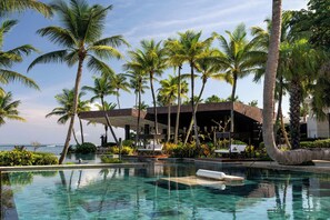 A pool area with palm trees, lounge chairs, and a building with a modern design. - Dorado Beach, a Ritz-Carlton Reserve (Dorado)