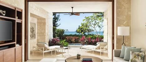 A spacious living area with a television, seating, and a view of the ocean.