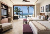 A hotel room with a balcony, a bed, a desk, and a TV.