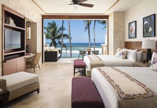 A hotel room with a balcony, a bed, a desk, and a TV.