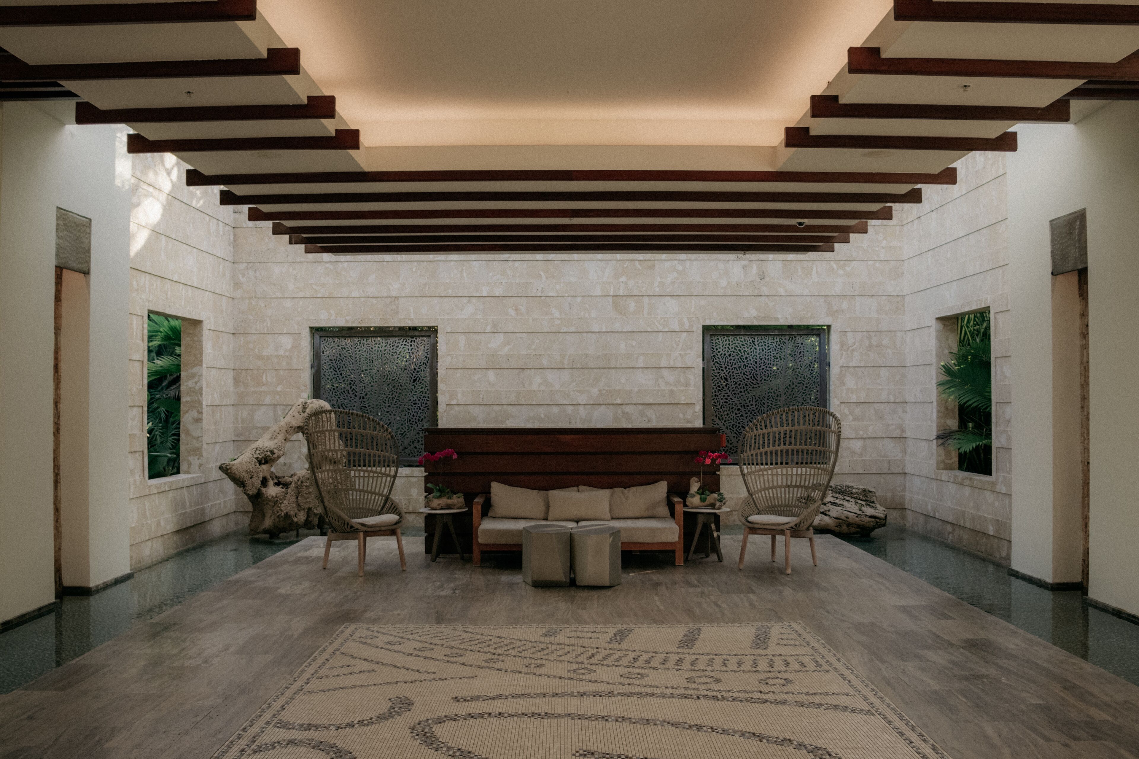 A spacious lobby with a central seating area, a patterned rug, and a stone wall.