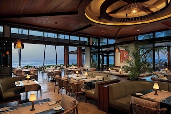 A modern beachfront property with a well-maintained lawn, palm trees, and a glass-enclosed building with a staircase leading to the entrance. at Dorado Beach, a Ritz-Carlton Reserve
