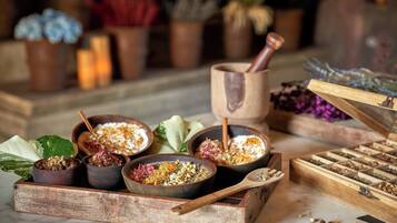 A wooden tray with bowls containing various food items and a wooden box with compartments of dried herbs.