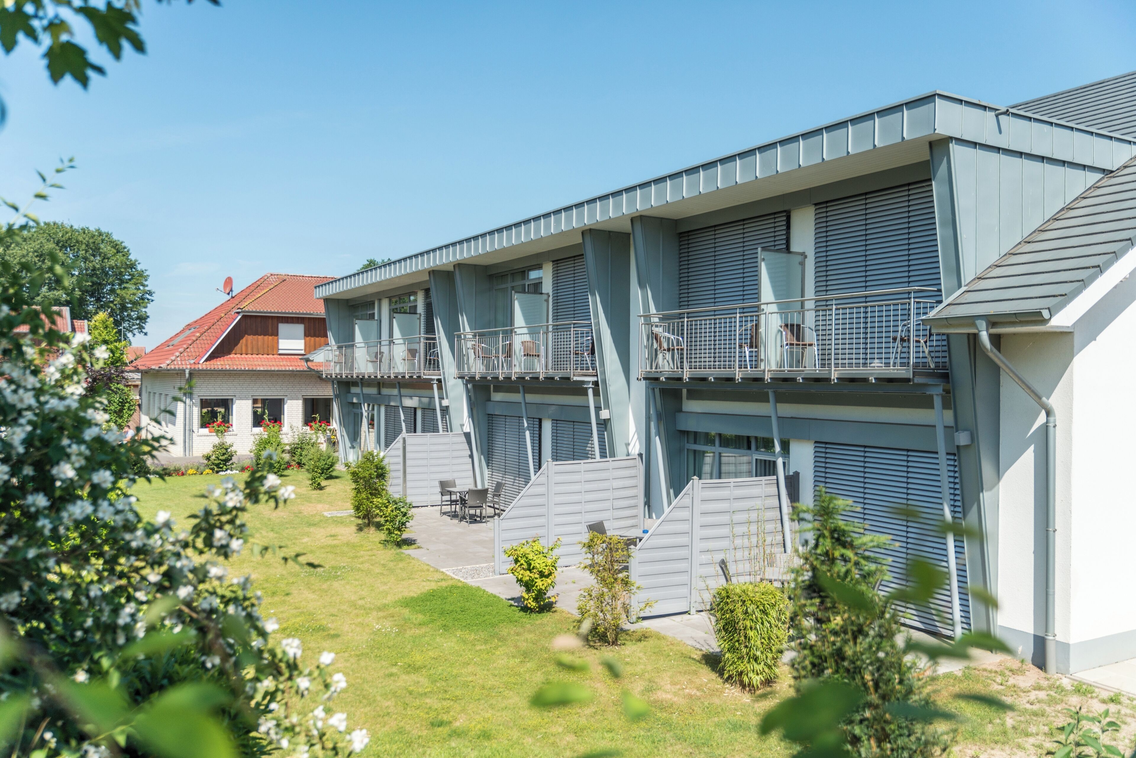 Un edificio moderno con varios balcones y un jardín.