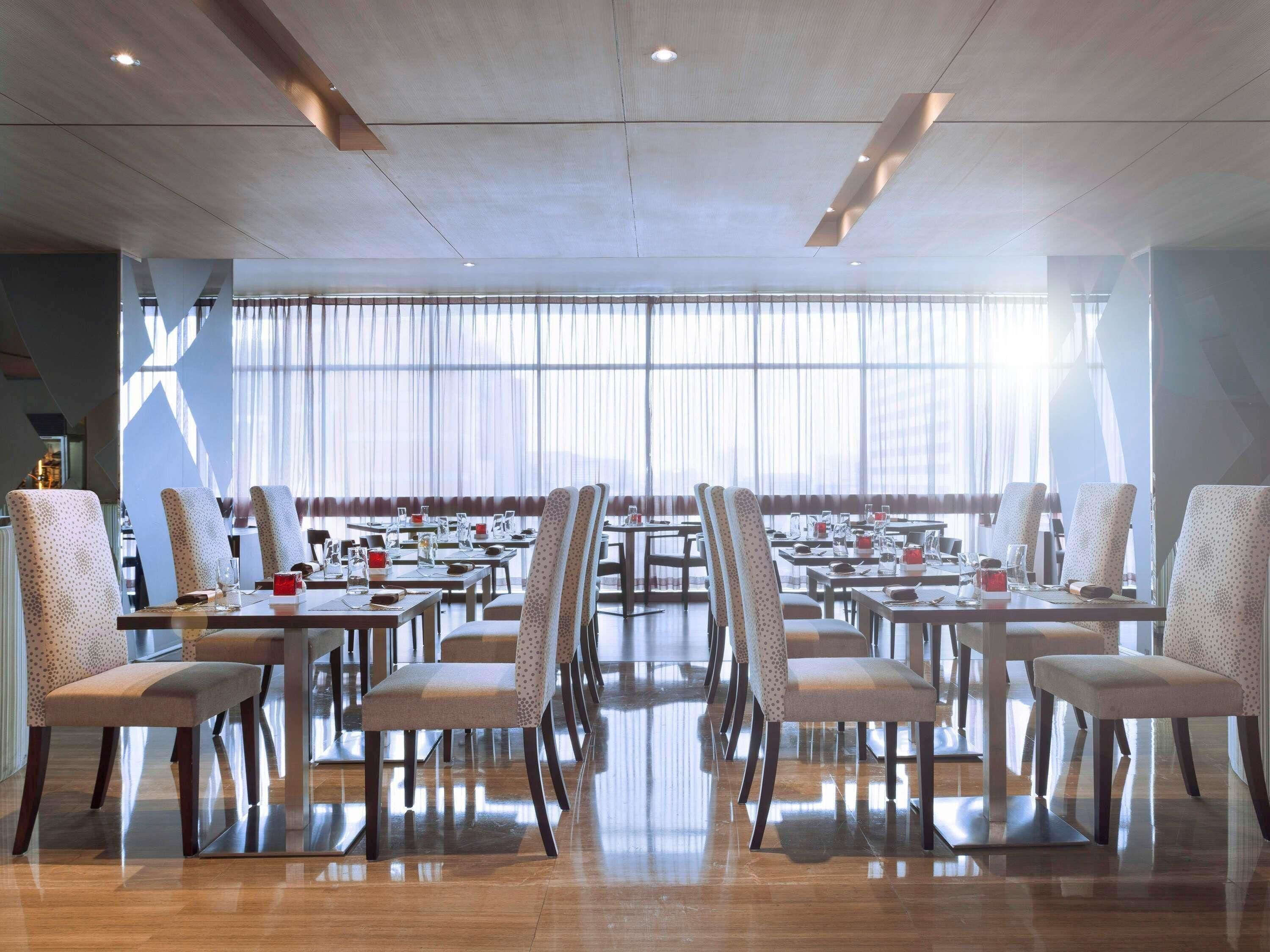 A conference room with tables and chairs, large windows, and a high ceiling.