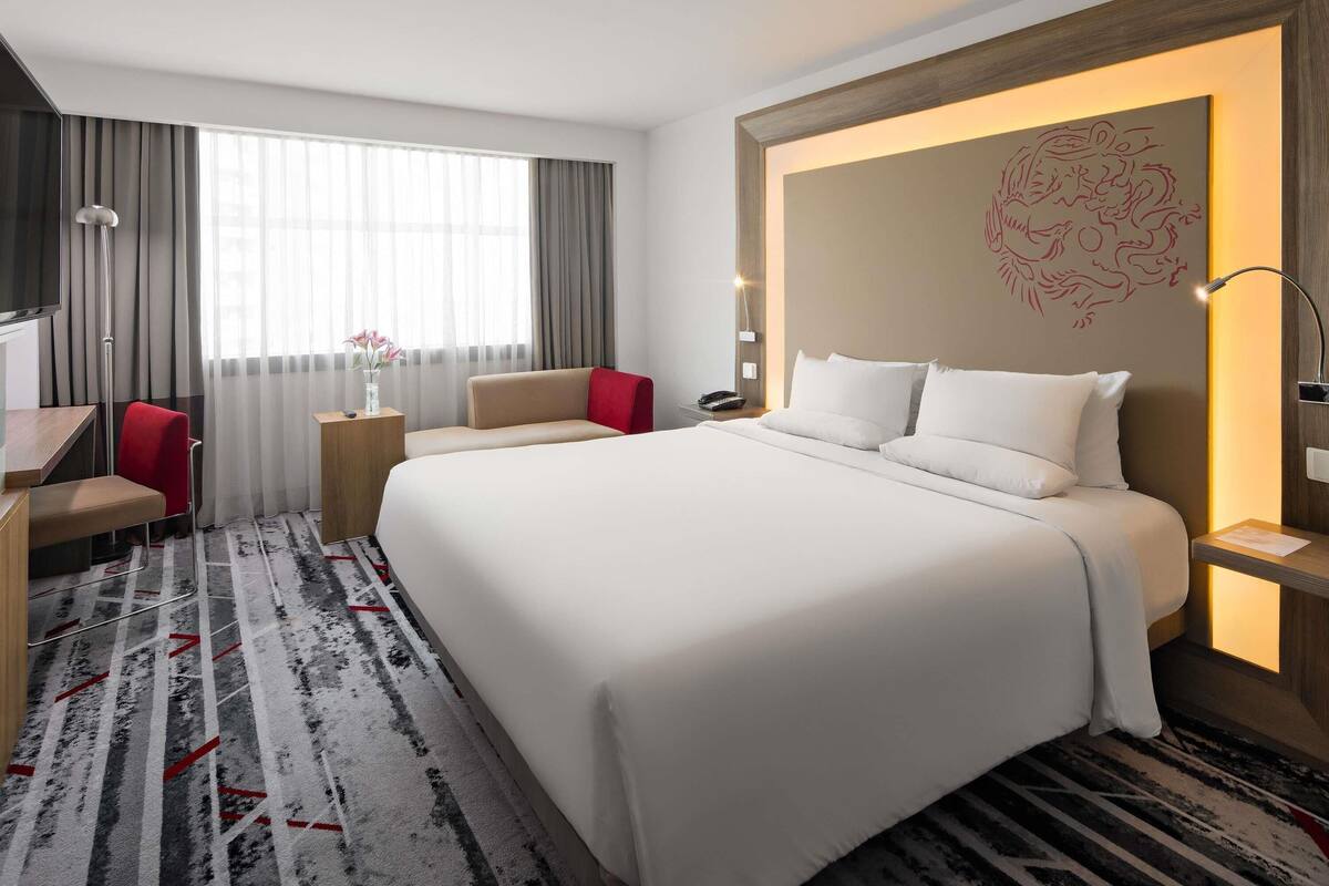Ein Hotelzimmer mit einem großen Bett, einem Schreibtisch, einem Stuhl und einem Fernseher.