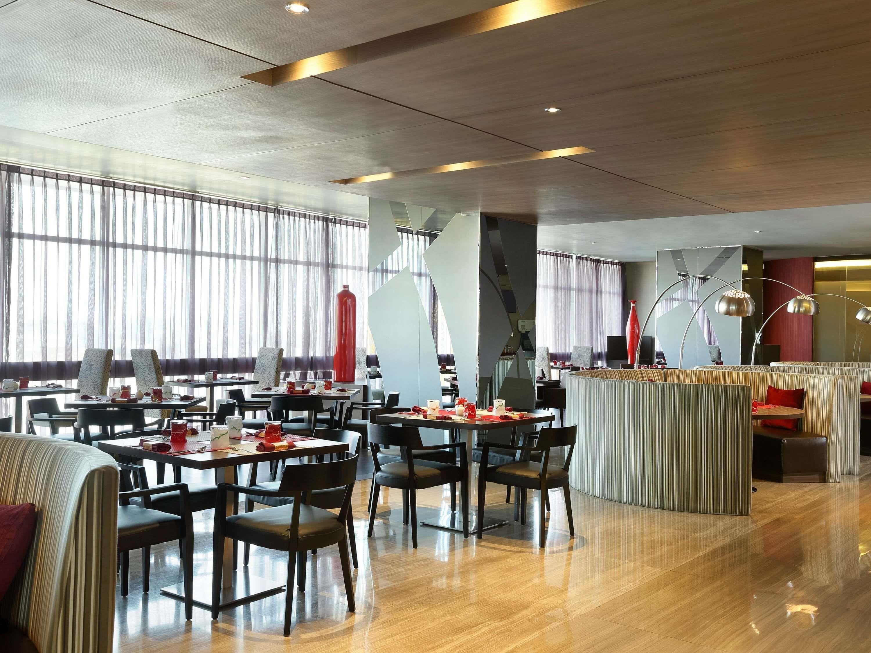 A modern restaurant with high ceilings, large windows, and contemporary furniture.
