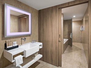 Une salle de bain moderne avec un grand miroir, un meuble-lavabo blanc et un espace douche.
