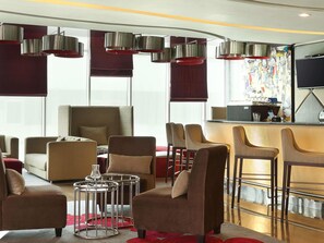 Ein Hotelzimmer mit Barbereich, Sitzgelegenheiten und großen Fenstern.