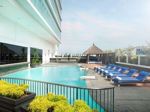 A rooftop pool with lounge chairs, a thatched-roof gazebo, and a modern building with large windows. - Novotel Jakarta Gajah Mada (Jakarta)