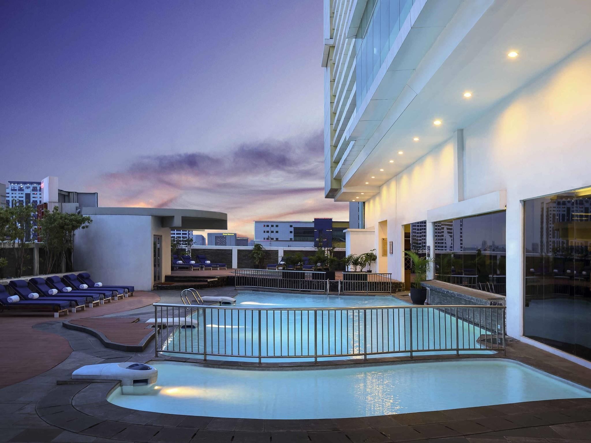 Un área de piscina en la azotea con sillones de descanso y una piscina.