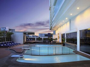 Un espace piscine aménagé sur le toit, avec des chaises longues et une piscine.
