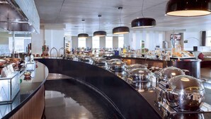 Eine moderne Hotelhalle mit gebogener Rezeption, einem Buffetbereich und großen Pendelleuchten.