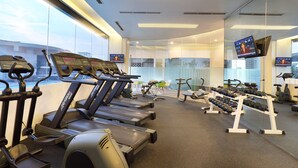 Ein Fitnessstudio mit Laufbändern, Kurzhanteln und Trainingsgeräten.
