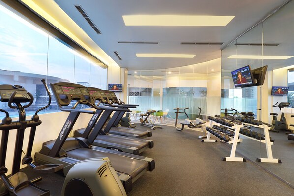 Ein Fitnessstudio mit Laufbändern, Kurzhanteln und Trainingsgeräten.