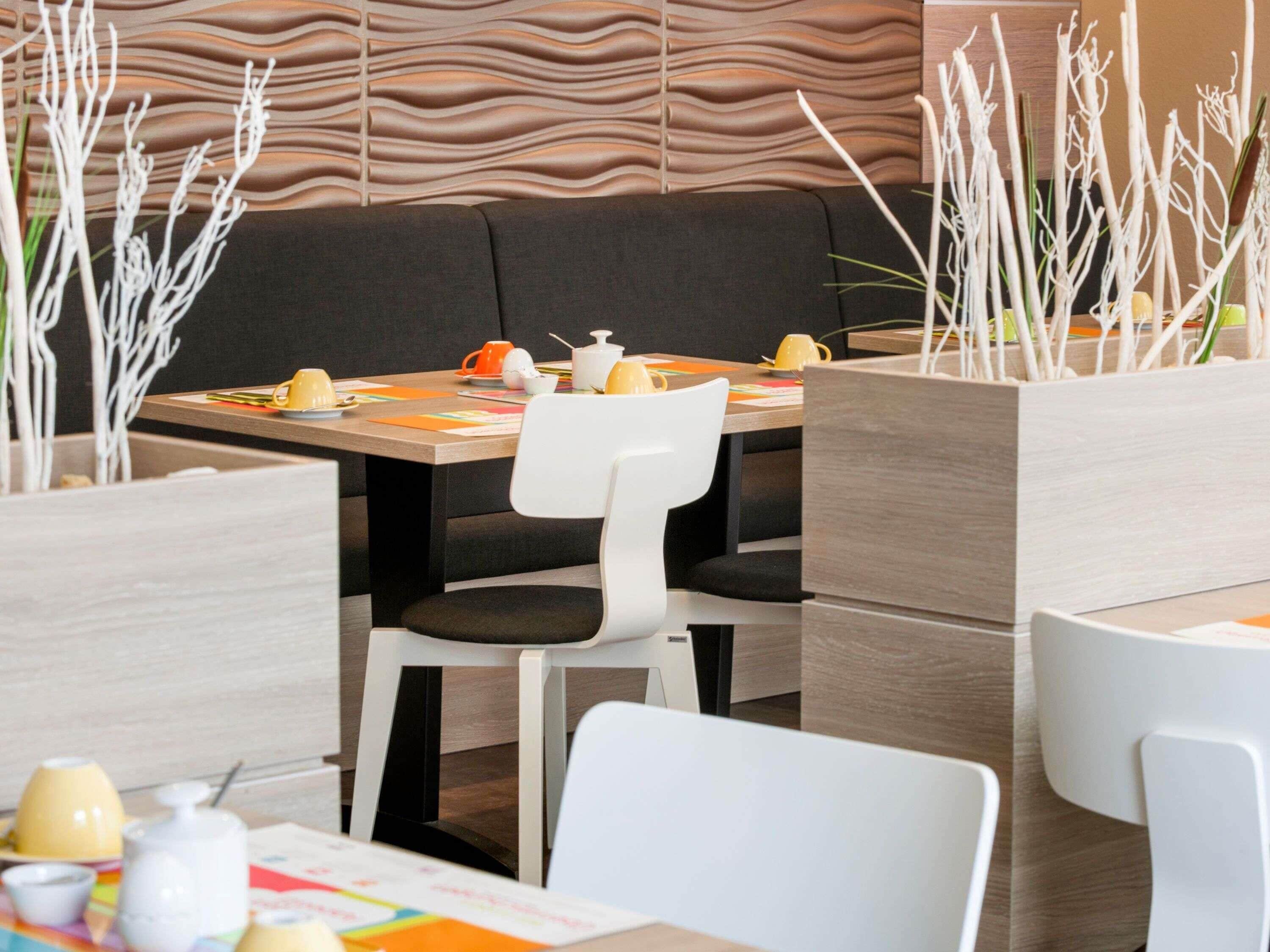 A modern dining area with a wooden table, white chairs, and a black cushioned bench.
