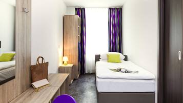 Ein Hotelzimmer mit Bett, Schreibtisch, Stuhl, Kleiderschrank und einer Badezimmertür.