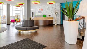 A modern lobby with a reception desk, seating area, and a staircase.