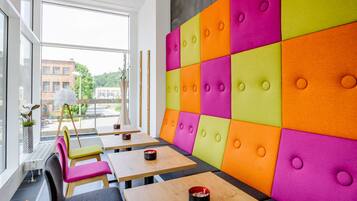 Un interior moderno con paneles acolchados de colores, mesas y sillas de madera.