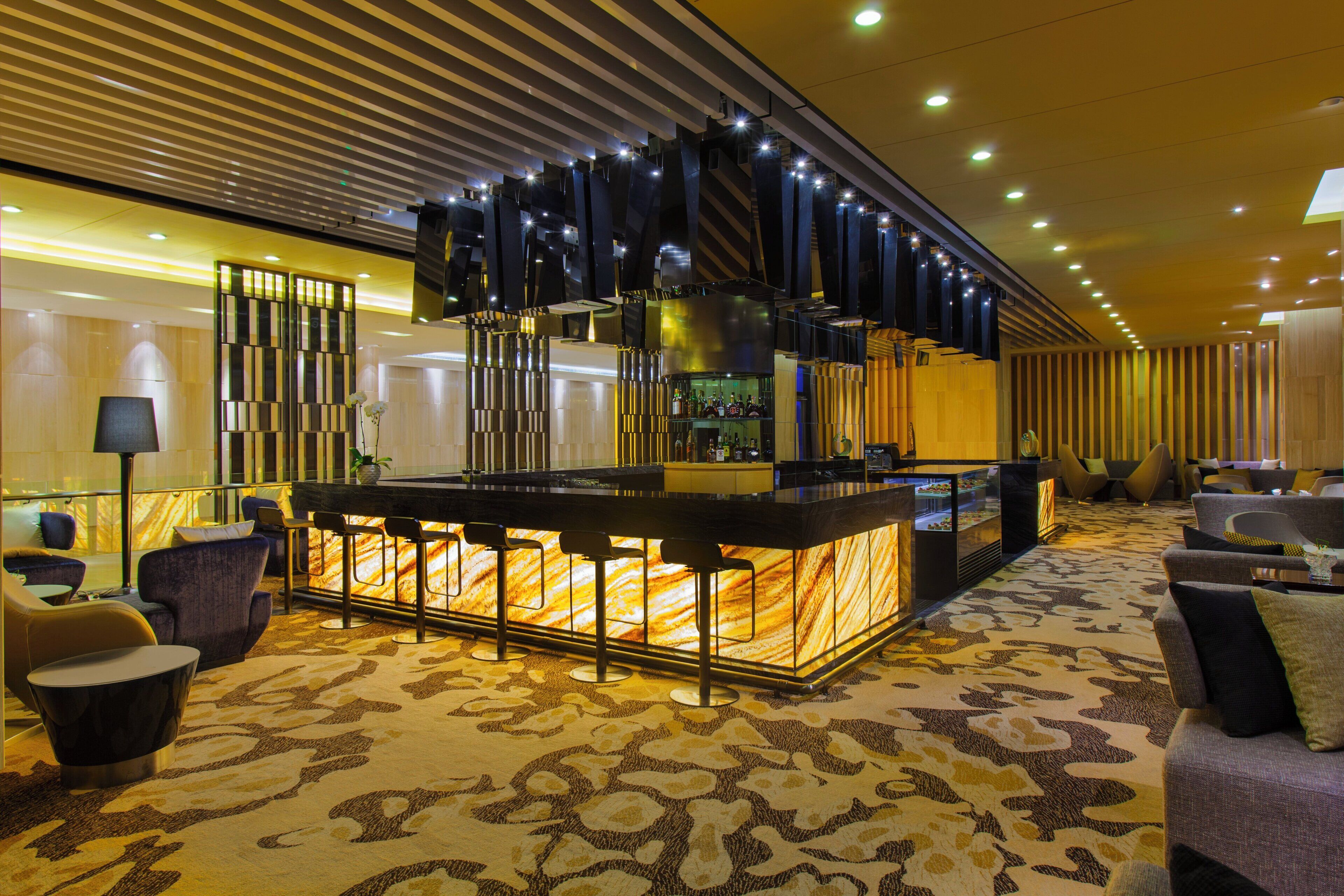 A bar area with a marble countertop, bar stools, and a decorative wall with vertical panels.