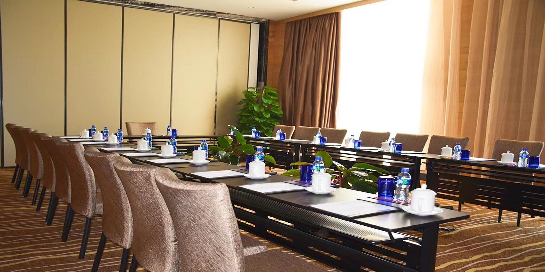 A conference room with long tables, chairs, and water bottles.