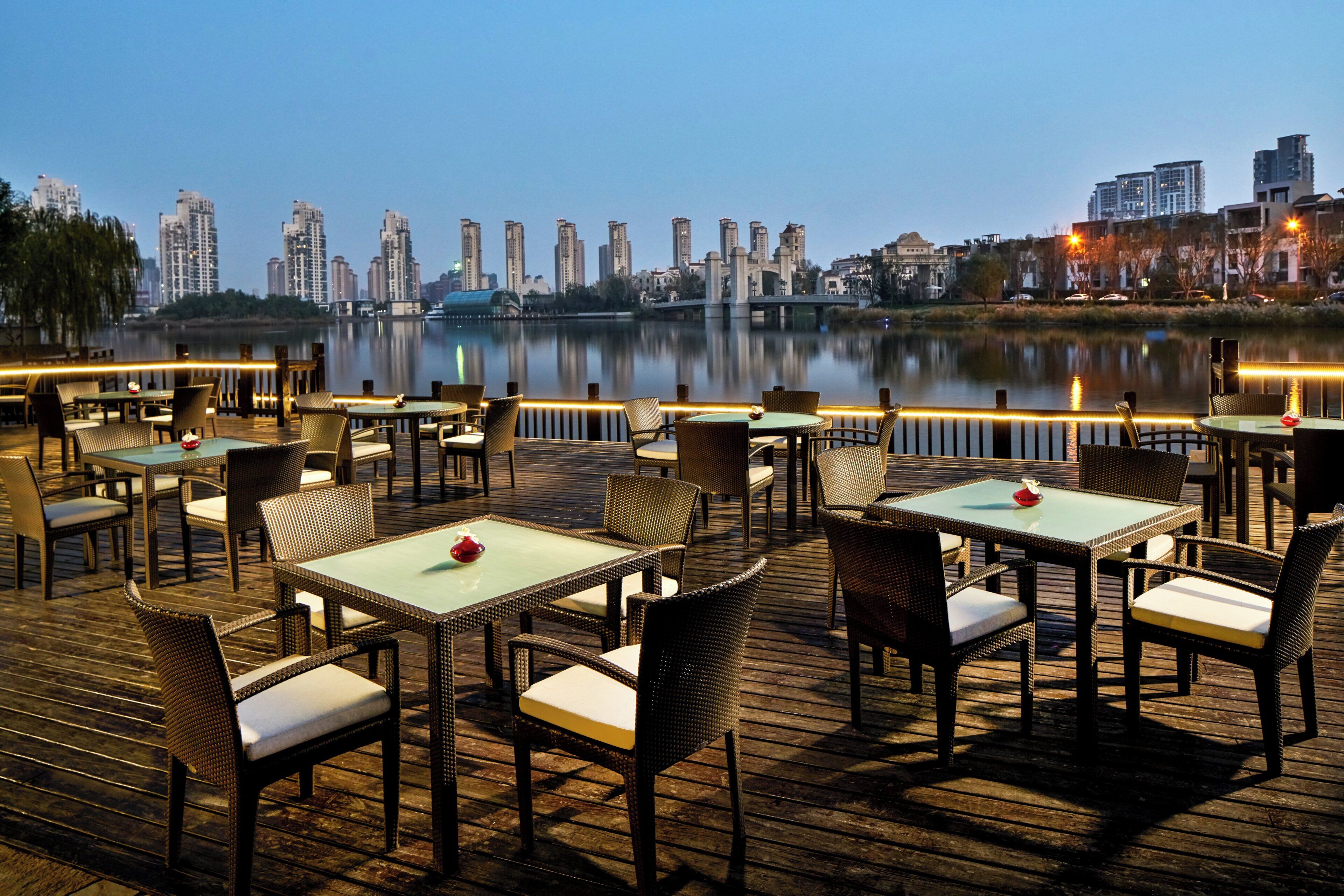Een restaurant aan het water met terras en uitzicht op de stadshemel.