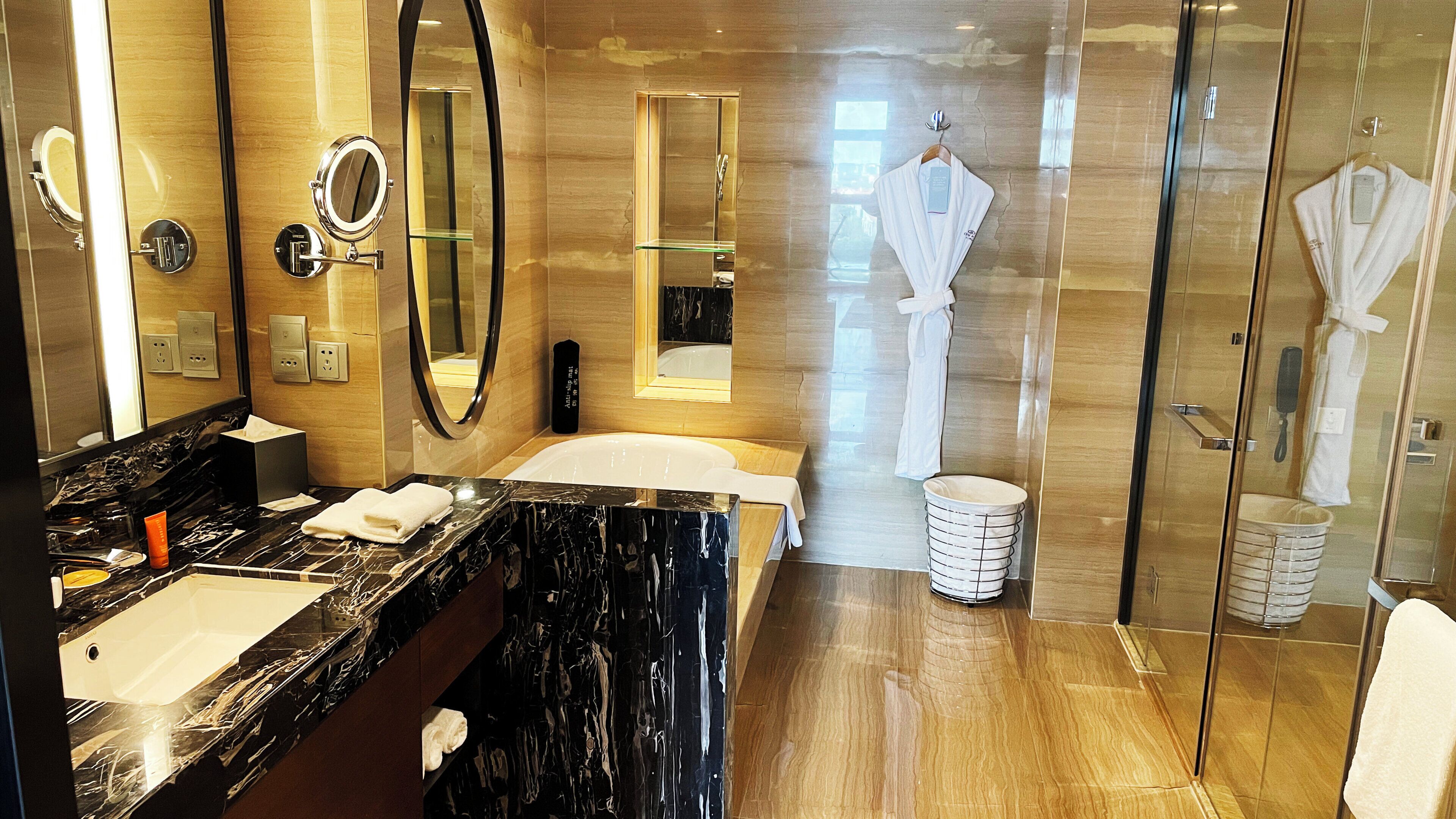 Une salle de bain moderne avec un lavabo en marbre, un grand miroir, une douche en verre et des serviettes blanches.