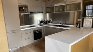 Una cocina moderna con electrodomésticos de acero inoxidable, horno empotrado y dispensador de agua.