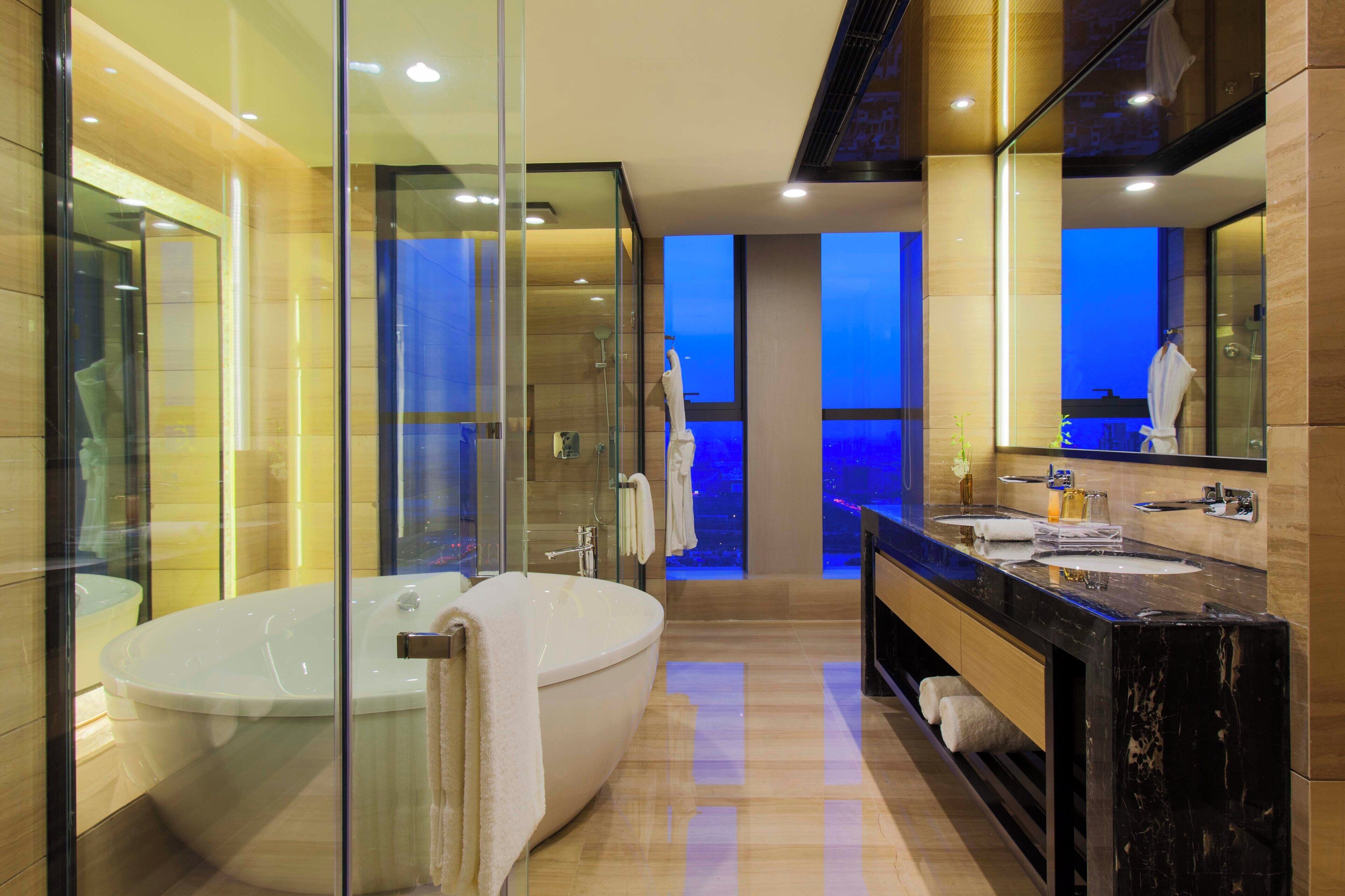 A modern bathroom with a large bathtub, a glass-enclosed shower, and a vanity with a mirror.