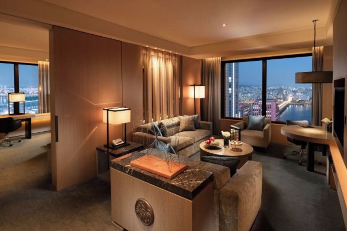 Une chambre d’hôtel moderne avec vue sur la ville, comprenant un canapé, une table basse et un espace bureau.