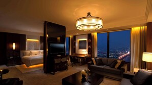 A modern hotel room with a large bed, a desk, a sofa, and a television. The room has a city view and a chandelier. - Conrad Seoul (Seoul)
