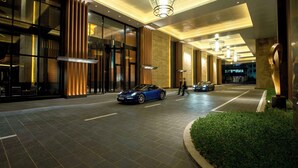 A modern hotel entrance with a blue sports car parked in the driveway, large glass windows, and a well-lit interior. - Conrad Seoul (Seoul)