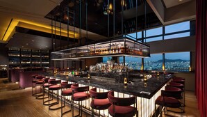 A modern bar with a high ceiling, a city view, and a variety of seating options. - Conrad Seoul (Seoul)