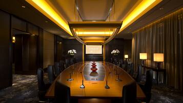 A conference room with a long table, chairs, and a podium.