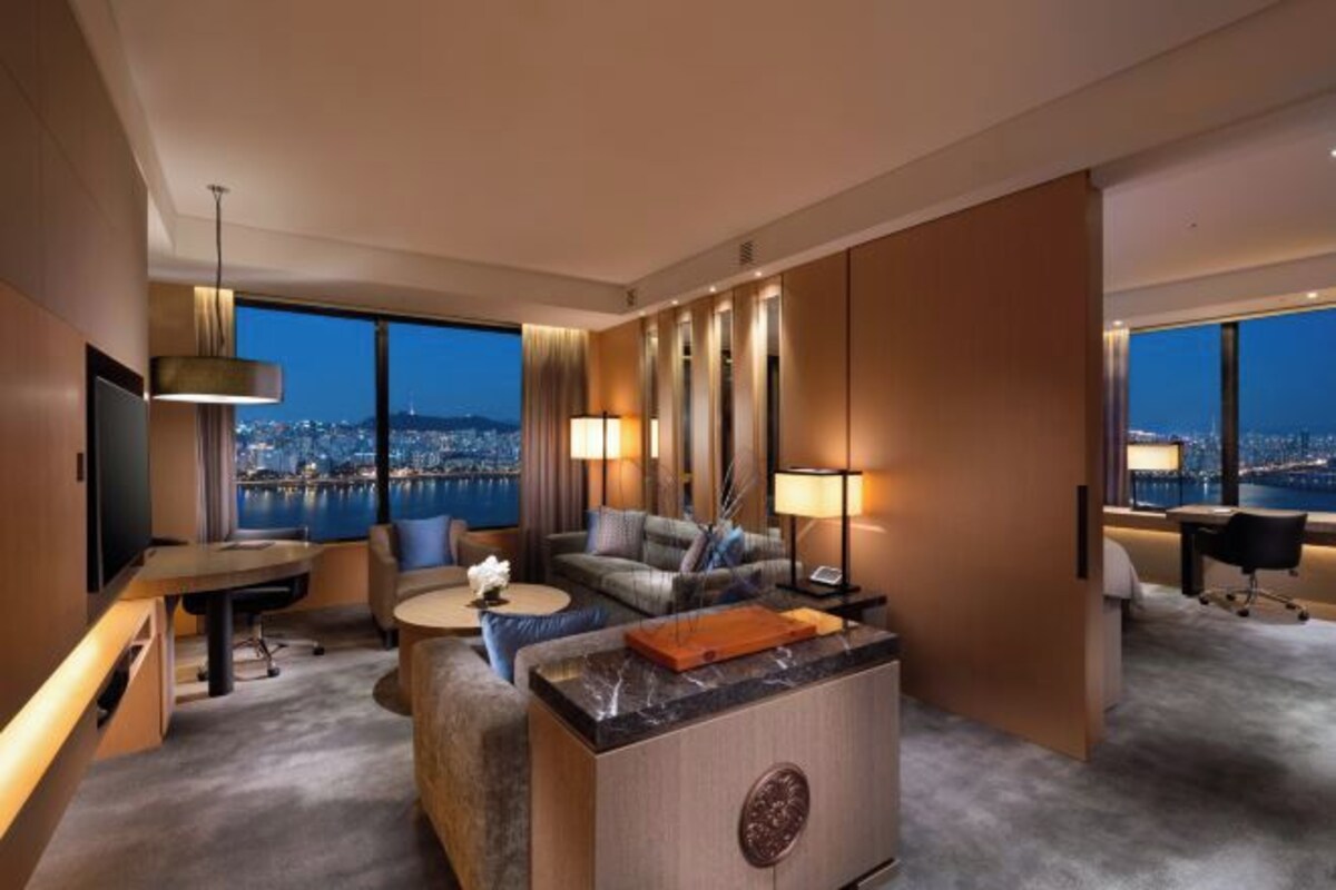 Une chambre d’hôtel moderne avec vue sur la ville, comprenant un canapé, un bureau et un coin repas.