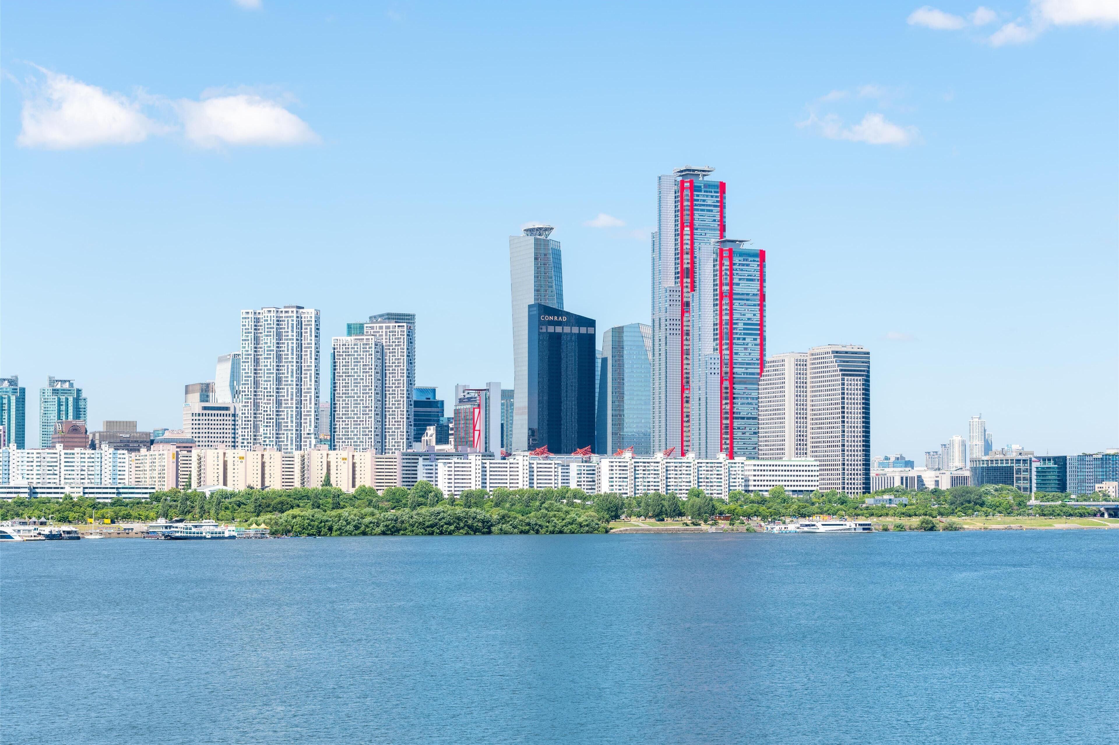 A city skyline with high-rise buildings, a waterfront, and a clear sky.