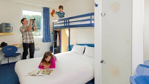 Une chambre d’hôtel avec un lit superposé, un bureau avec une télévision et une chaise.