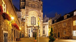 Eine Kopfsteinpflasterstraße führt zu einem historischen Gebäude mit großem Bogenportal und einem Glockenturm.